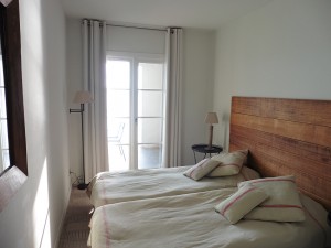 Second bedroom with 2 single beds and french doors which open onto covered terrace overlooking the water