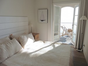 Main bedroom with very large double bed and french doors which open onto covered terrace overlooking the water